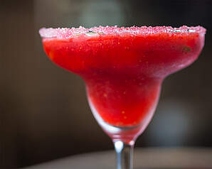 Strawberry Daiquiri i cocktailglas med dyb rød jordbærfarve og dekorativ sukkerkant
