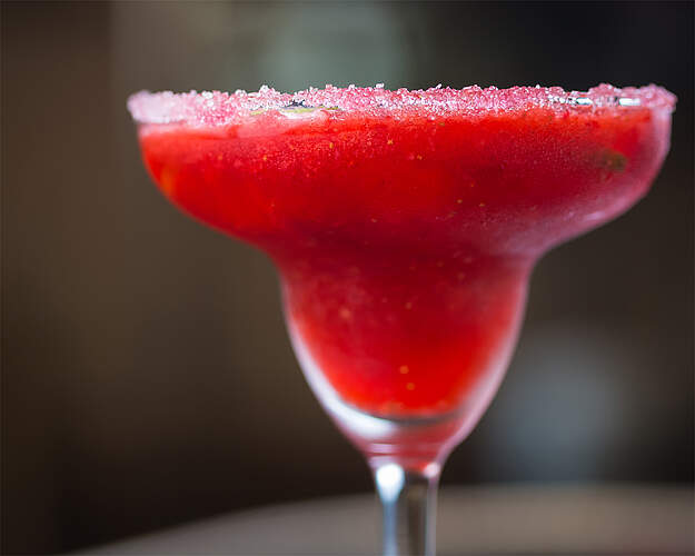 Strawberry Daiquiri i cocktailglas med dyb rød jordbærfarve og dekorativ sukkerkant