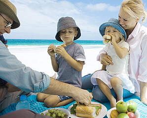 Familie spiser sammen ved en sommerpicnic på stranden