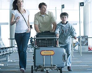 Familie med bagage i lufthavn som illustration til artikel om flyforsinkelser, aflysninger og passagerrettigheder