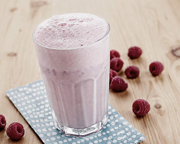 Hindbærshake i glas med friske hindbær på træbord