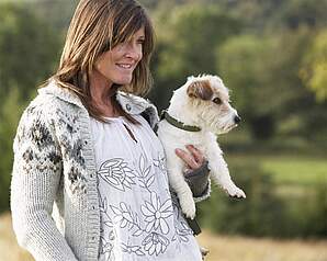 Kvinde holder lille hund i naturen som illustration til valg af hund senere i livet