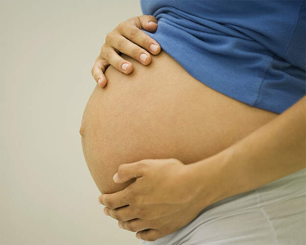 Gravid kvinde med hænderne på maven - overvægt kan påvirke fertilitet og graviditet